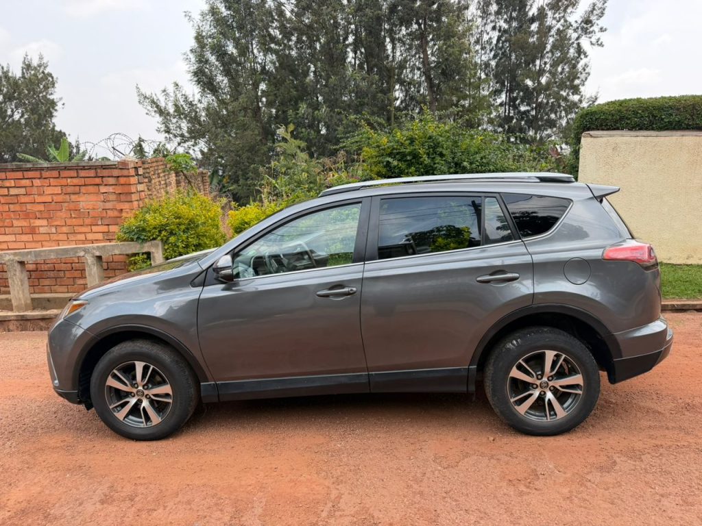 Toyota RAV4 rental car parked overlooking a lush green tea plantation during a self-drive car hire tour in Rwanda